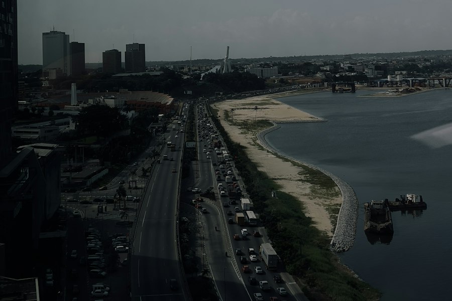 Vue aérienne d'une avenue d'Abidjan longeant la lagune, avec les immeubles du Plateau en arrière-plan