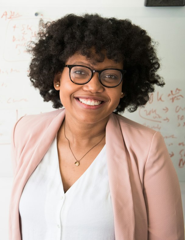 Portrait d'Adjoua Bamba, cheffe de projet événementiel, souriante devant un tableau blanc
