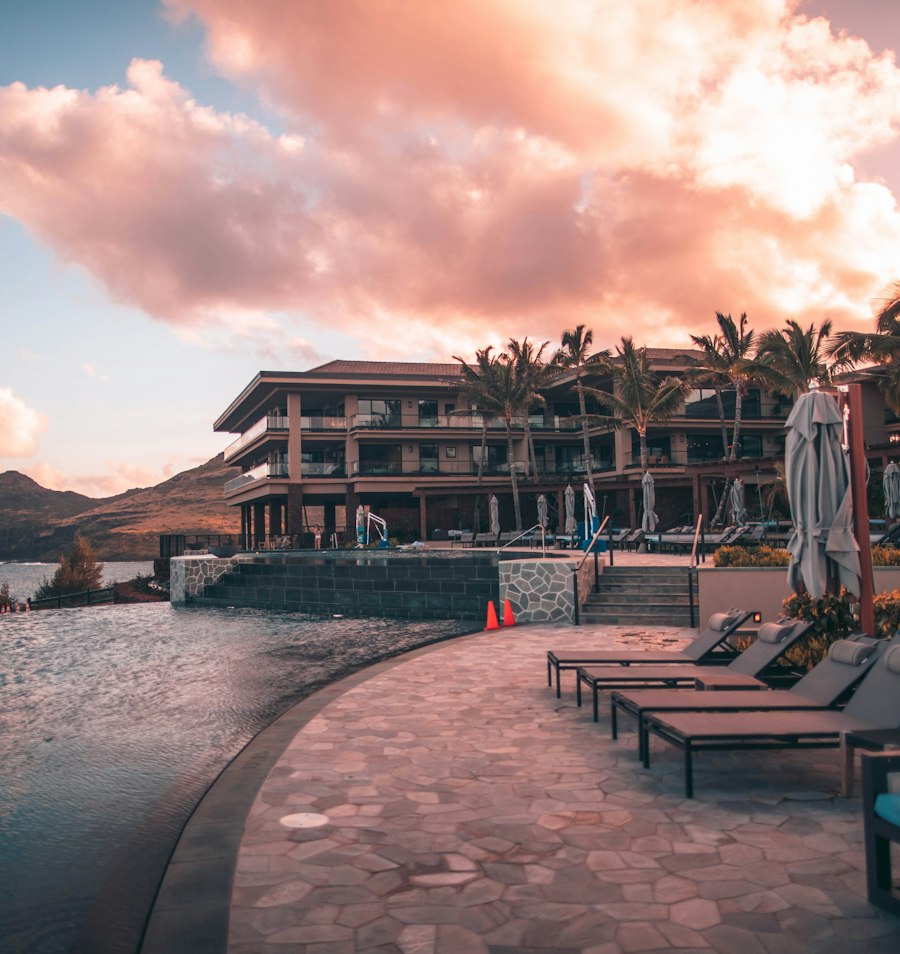Hôtel de bord de mer et sa piscine à débordement au coucher du soleil, entourés de palmiers