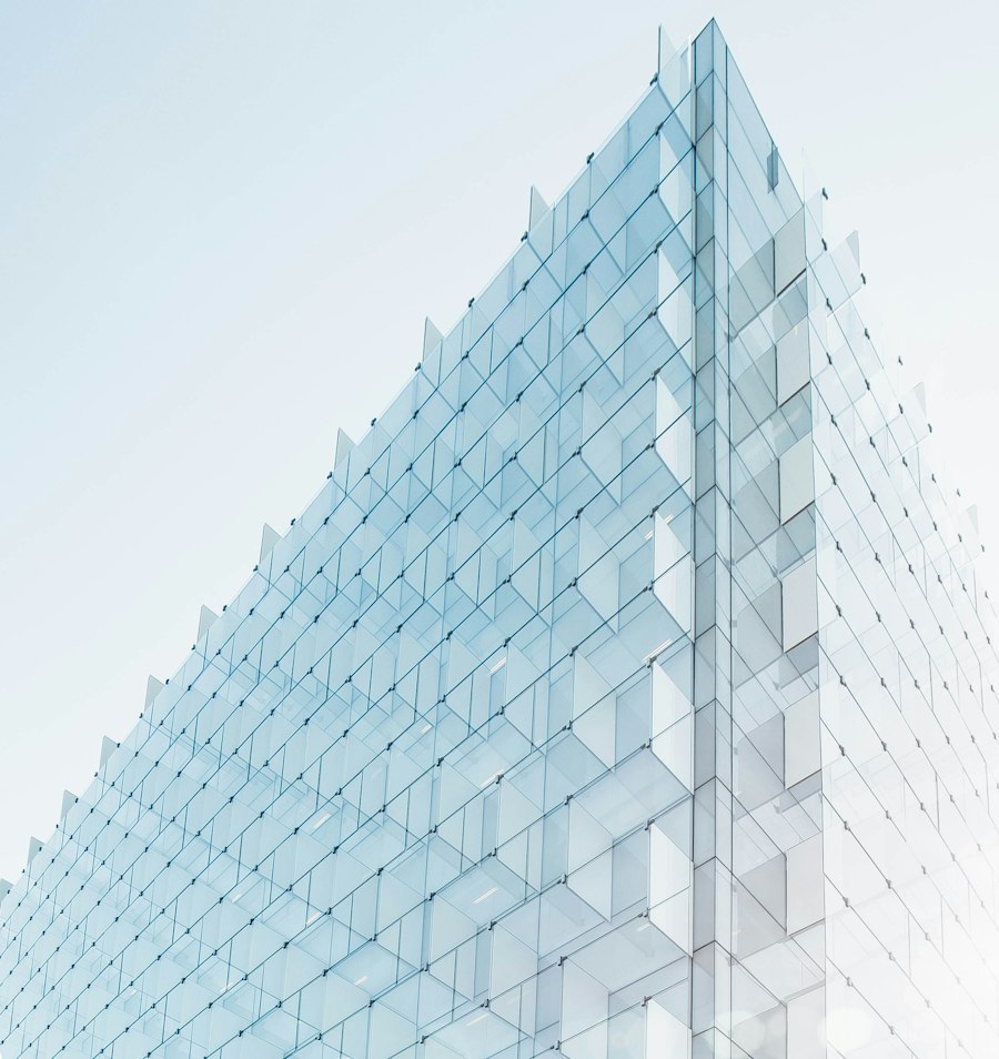 Façade vitrée d'un immeuble de bureaux moderne sous un ciel clair, symbole de solidité et de transparence