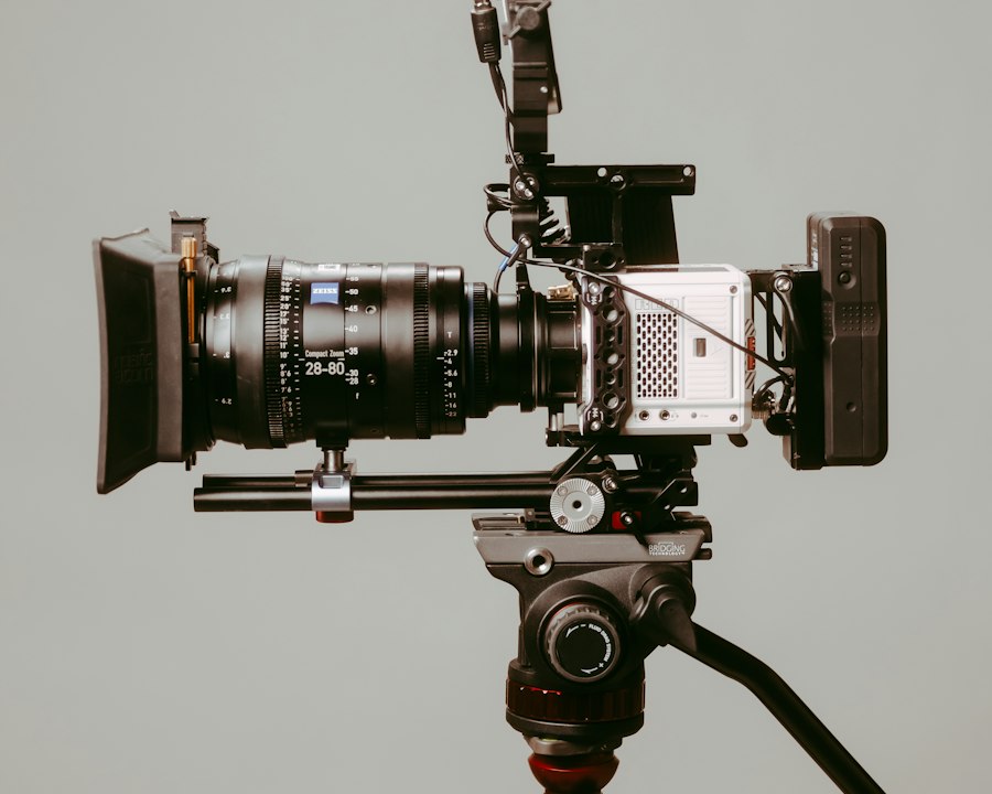 Caméra de cinéma équipée d'un objectif et d'un moniteur, montée sur un trépied devant un fond gris