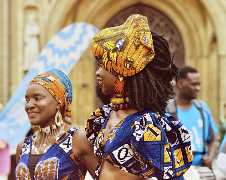 Deux femmes en tenues wax colorées et coiffes assorties, souriantes, lors d'un événement en extérieur